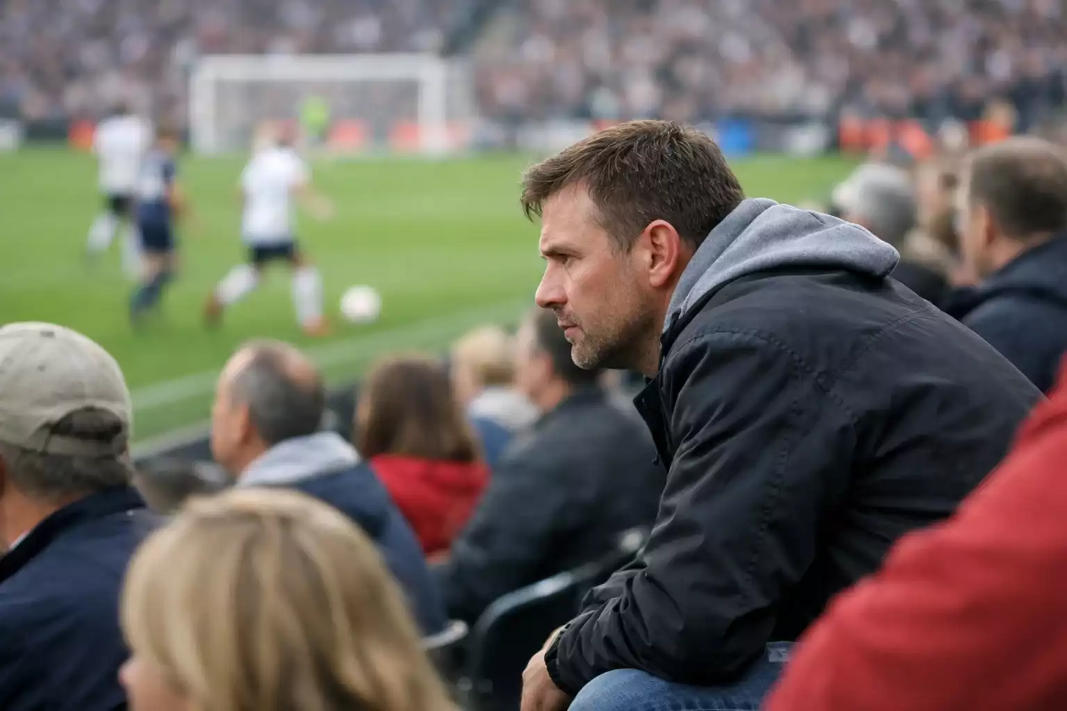 Fan kijkt aandachtig naar voetbalwedstrijd in stadion